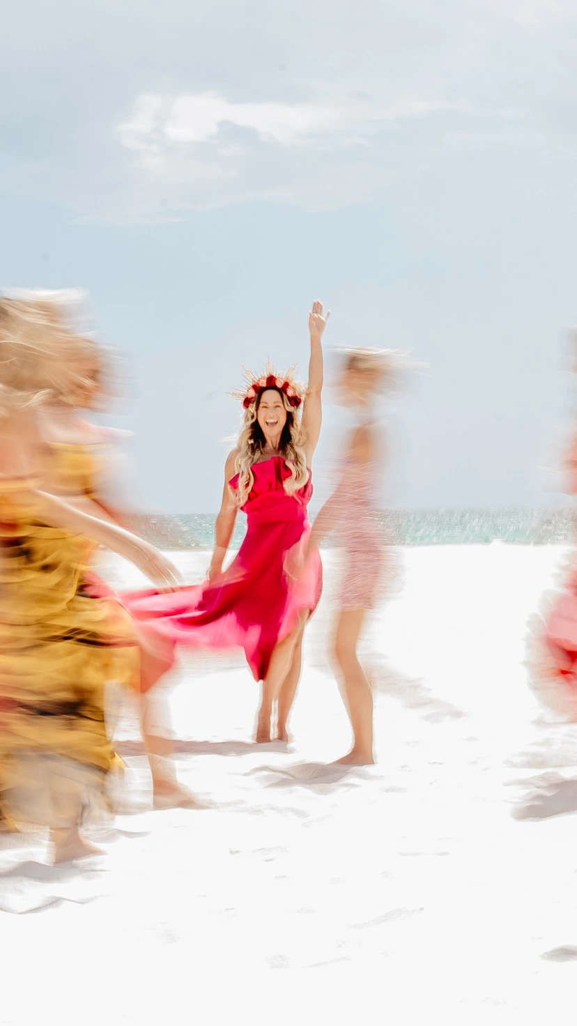 Vanessa Lambert laughing with arm raised, women in motion around her on the beach