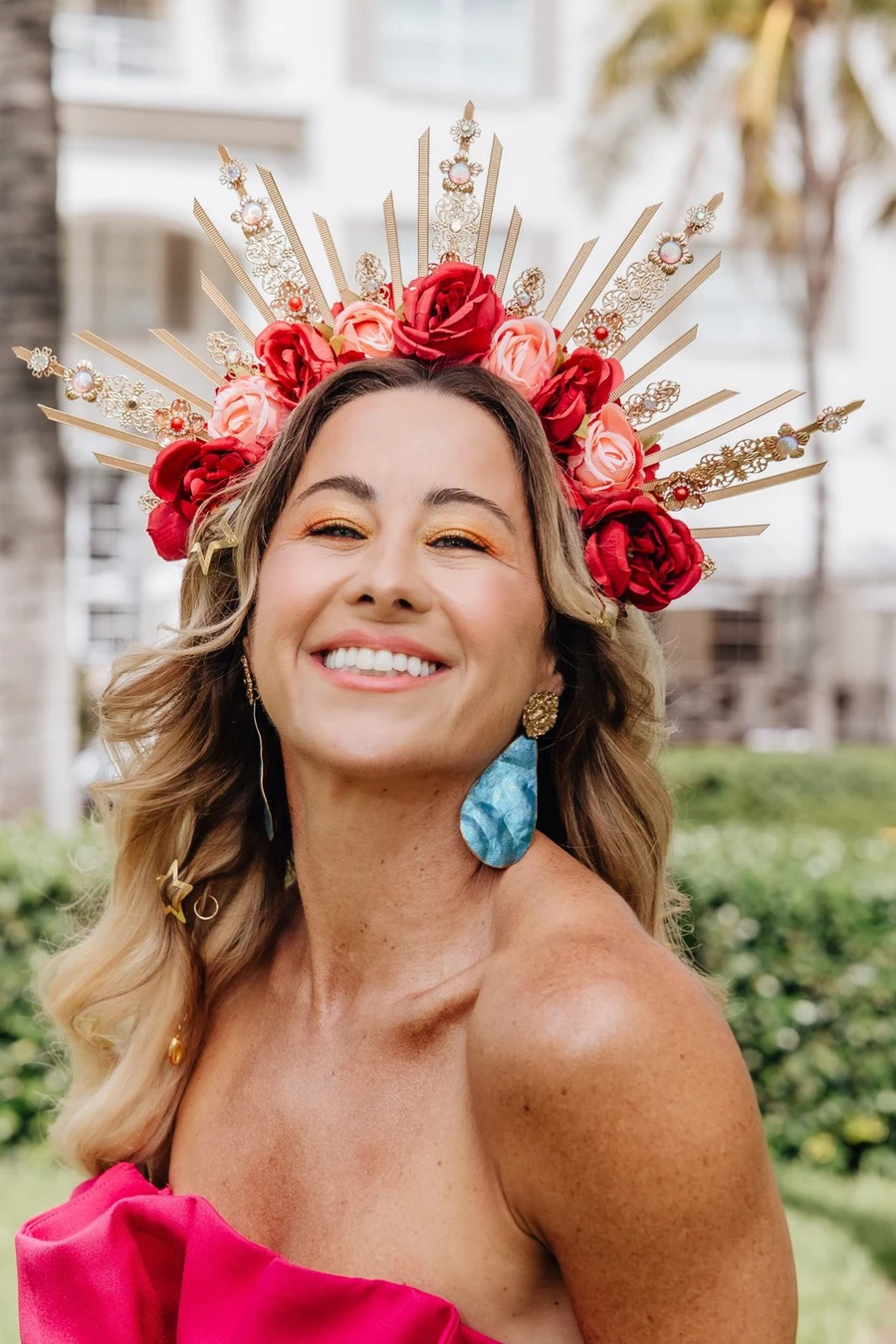 Vanessa Lambert in a hot-pink gown and a gold-and-rose sunburst crown on the lawn at The Betsy