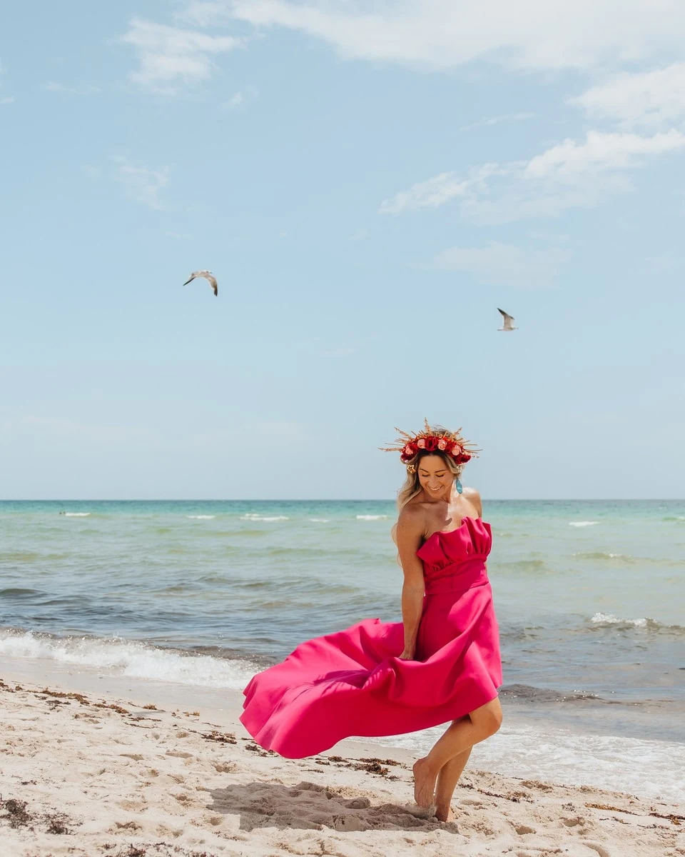 Vanessa on the beach in a pink gown, flower crown, gulls overhead