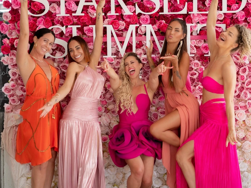 Five women laughing together at the Starseed Summit flower wall