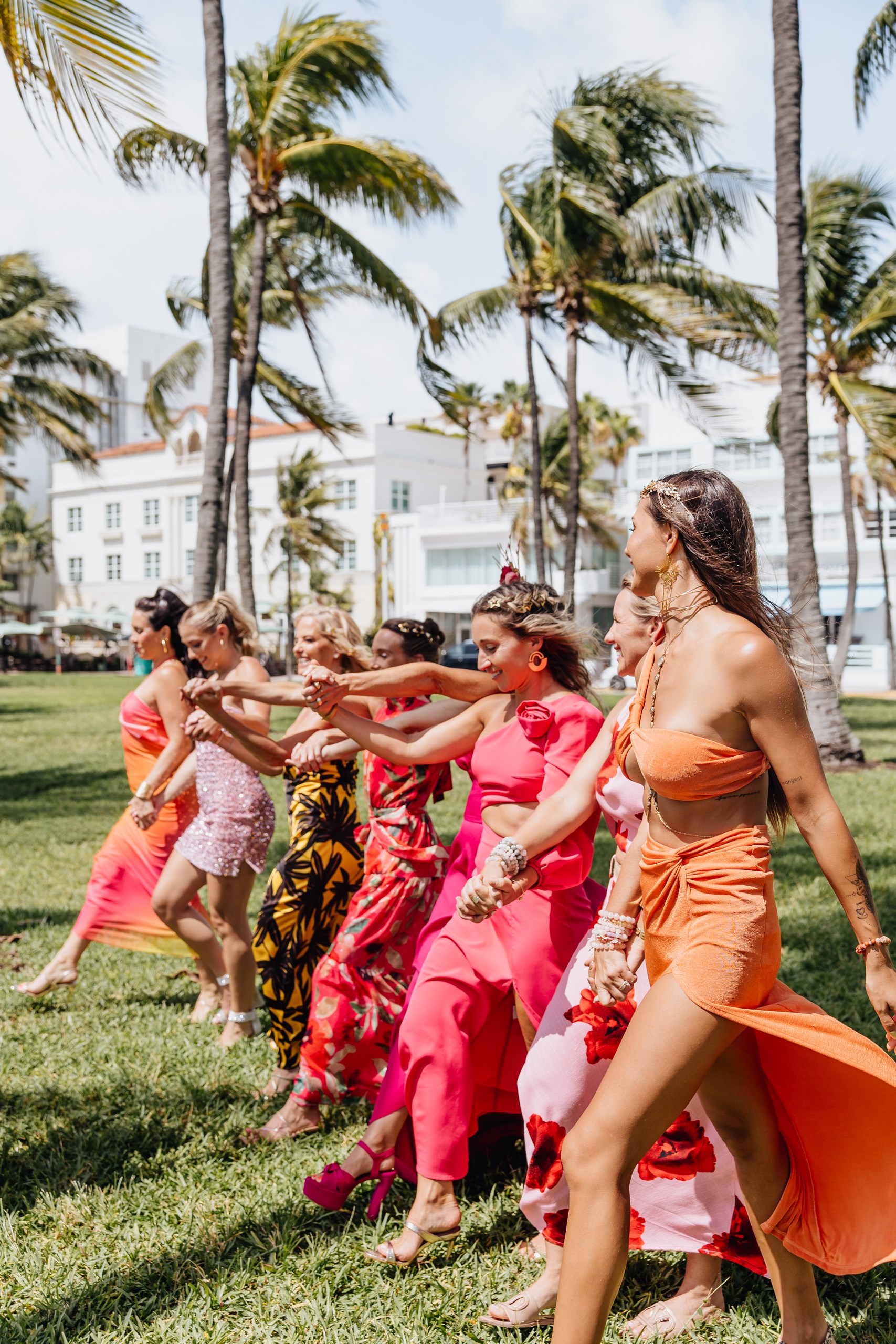 Women walking hand in hand along a palm-lined path at Starseed Summit